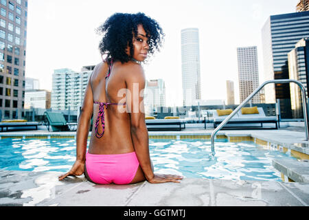 Schwarze Frau sitzen am Pool mit Blick auf Schulter Stockfoto
