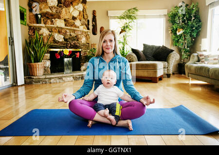 Mutter meditieren Gymnastikmatte mit Baby im Schoß Stockfoto
