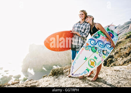 Kaukasische paar Surfbretter am Strand tragen Stockfoto