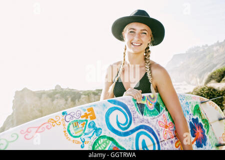 Kaukasische Frau mit Surfbrett am Strand Stockfoto