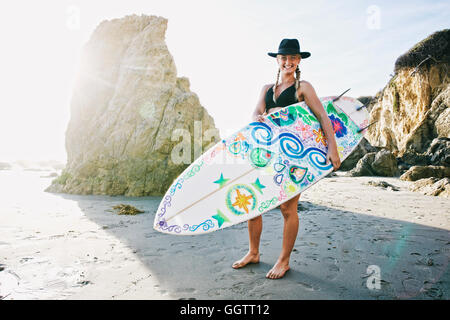 Kaukasische Frau mit Surfbrett am Strand Stockfoto