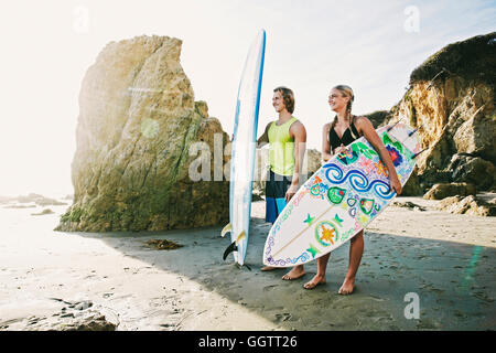 Kaukasische paar Surfbretter am Strand tragen Stockfoto