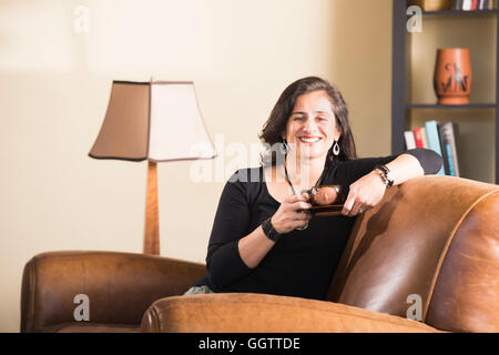 Hispanic Frau im Sessel, Kaffee trinken Stockfoto