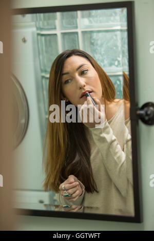 Frau Auftragen von Lippenstift im Spiegel Stockfoto