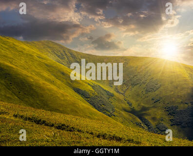 grünen Rasen am Hang Wiese im Hochgebirge unter bewölktem Himmel im Abendlicht Stockfoto