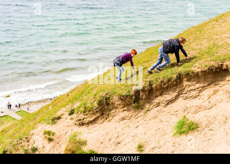 Kaseberga, Schweden - 1. August 2016: Junger Erwachsener Mann und Frau besteigen einen steilen sandigen Hügel aus das Meer. Realen Lebenssituation Stockfoto