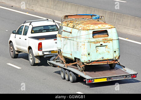 Abschleppen von rostigen alten van Trailer UK Autobahn England mit Pickup-Truck transportiert Nummernschilder verdeckt Stockfoto