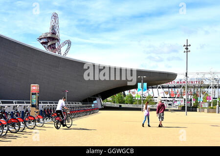 Person Reiten von Santander Fahrrad mieten docking-Station am Aquatic Centre mit Orbit Turm darüber hinaus im Queen Elizabeth Olympic Park Stratford in London UK Stockfoto