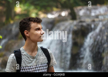 Junger Mann Wanderer mit Rucksack in der Nähe eines Wasserfalls Stockfoto