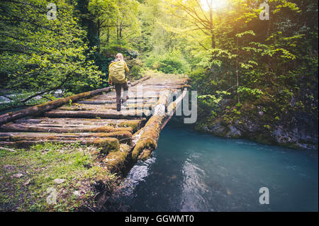 Woman Traveler mit Rucksack wandern auf Brücke über Fluss Reisen Lifestyle Konzept Wald auf Hintergrund Reise Sommerferien Stockfoto