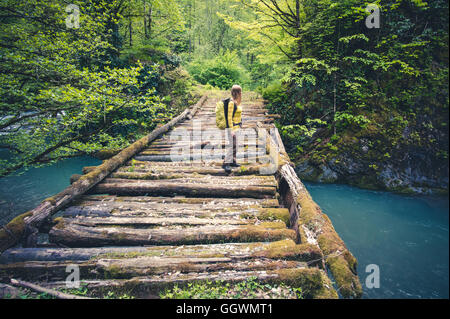 Woman Traveler mit Rucksack wandern auf Brücke über Fluss Reisen Lifestyle Konzept Wald auf Hintergrund Reise Sommerferien Stockfoto