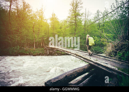 Woman Traveler mit Rucksack wandern auf Brücke über Fluss Reisen Lifestyle Konzept Wald auf Hintergrund Reise Sommerferien Stockfoto