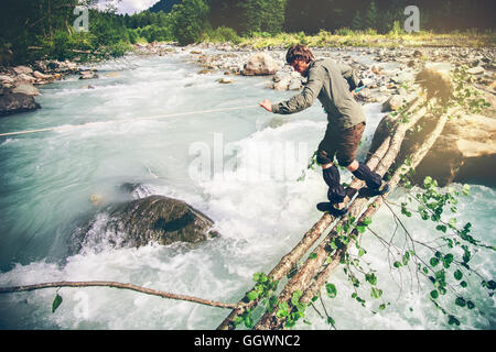 Mann Reisenden überqueren Fluss im Wald Outdoor-Lifestyle Reisen extreme Survival-Konzept Stockfoto