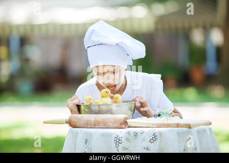 Schockiert kleine Chef zeigt Entenküken in eine Schüssel geben, beim Kochen im freien Stockfoto