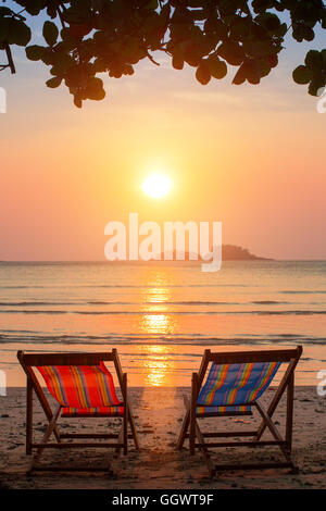 Ein paar Sonnenliegen am Strand bei Sonnenuntergang. Stockfoto