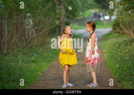 Zwei kleine süße Freundinnen lebhaft im Gespräch im Park. Stockfoto