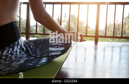 Nahaufnahme von Frau sitzt mit gekreuzten Beinen und Händen auf Knien auf Trainingsmatte. Meditieren im Lotus Pose am Yoga-Kurs, P weiblich Stockfoto