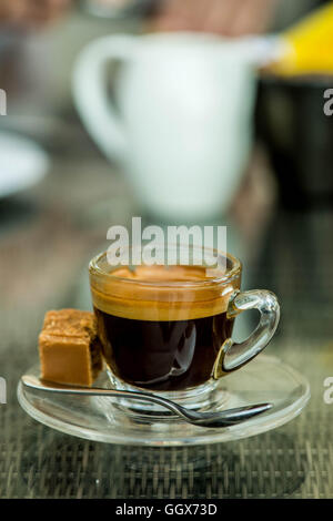 Beginnen Sie den Tag mit einem frisch gebrühten oder Tasse starken Erfrischende Single Shot Espresso in ein Glas Schale mit Fudge auf dem Tisch und keine Leute Stockfoto