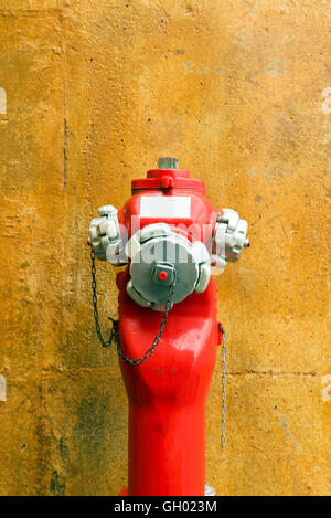 Eine Nahaufnahme zu einem roten Hydranten in der Nähe einer Wand Stockfoto