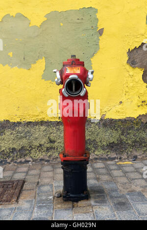 Eine Nahaufnahme zu einem roten Hydranten in der Nähe einer Wand Stockfoto