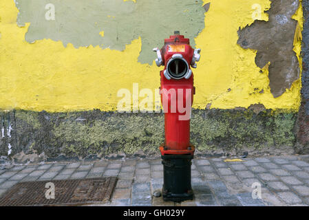 Eine Nahaufnahme zu einem roten Hydranten in der Nähe einer Wand Stockfoto