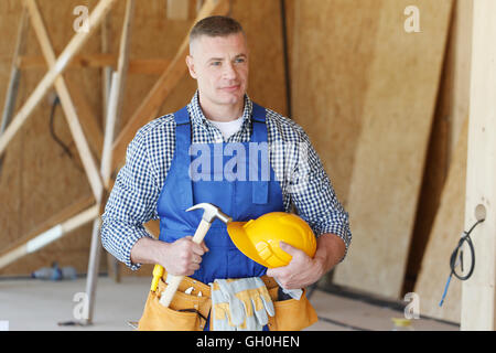 Bauarbeiter mit Hammer in der Hand und Werkzeuge auf Baustelle Stockfoto