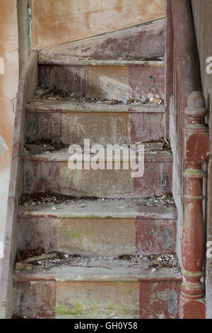 Vertikale Aufnahme einer vergessenen Holztreppe in einem leeren verlassenen Haus. Stockfoto