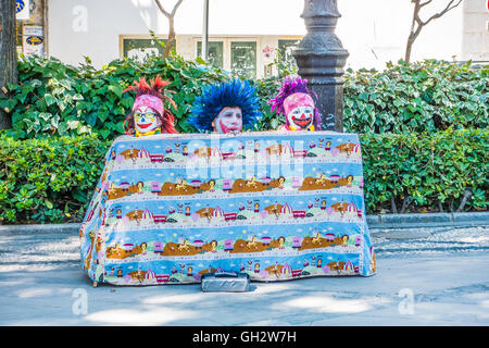 Eines Mannes, der Kopf und die Köpfe der beiden Dummys ausleben Straßenperformance Auspacken zu Pfannenstiel für Geld in Granada, Spanien. Stockfoto