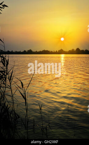 Landschaft mit Sonnenuntergang über dem See mit der Reflexion des Lichts auf der Oberfläche des Wassers Stockfoto