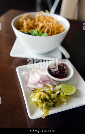 Khao Soi Rezept, Thailand nördlichen Stil Curry Nudelsuppe mit Huhn serviert mit Gemüse, Limette und Chili-paste Stockfoto