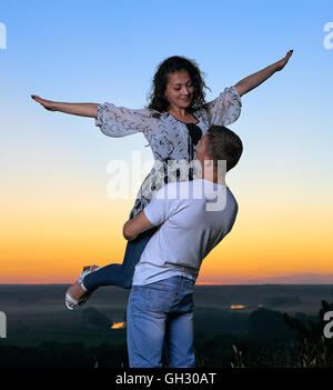 romantische Paare, die Spaß bei Sonnenuntergang im Freien, schöne Landschaft und hell gelb Himmel, liebe Zärtlichkeit Konzept, junger Erwachsener Stockfoto