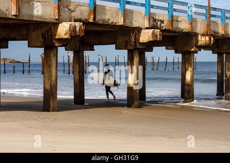 Surfer mit seinem Surfbrett am Strand entlang spazieren, am Morgen Stockfoto