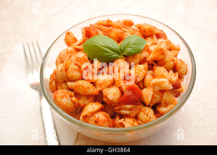 Eine Glasschüssel gefüllt mit Shell-Pasta mit Tomatensauce Stockfoto