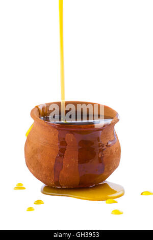 Honig in einer überquellenden Ton-Topf gießen. Isoliert auf weißem Hintergrund. Stockfoto