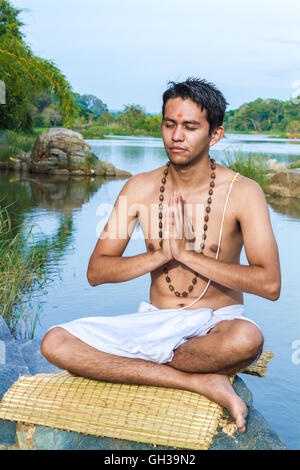 Ein junger Hindu Priester (Brahmanen) befindet sich im Gebet an einem Flussufer. Stockfoto