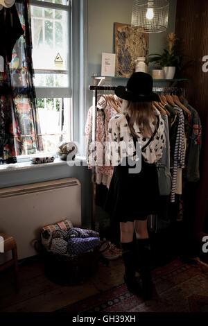 ein 12 Jahres altes Mädchen trägt einen schwarzen Hut in einem Vintage-Kleidung Shop durchsuchen Stockfoto