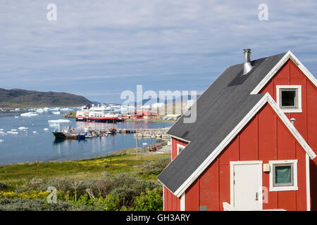 Roten grönländischen Holzhaus mit Blick auf Hafen im Tunulliarfik-Fjord mit Eisberge schwimmen im Sommer. Narsaq Grönland Stockfoto