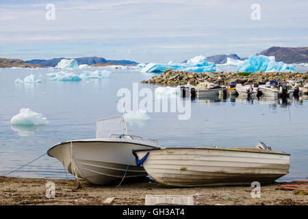 Kleine Fischerboote im Hafen von Qajaq mit Eisberge vor der Küste im Tunulliarfik-Fjord im Sommer. Narsaq Kujalleq Südgrönland Stockfoto