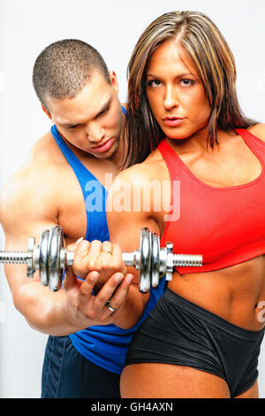 Fit Woman Ausübung mit einer Hantel mit Hilfe eines männlichen Partners Stockfoto