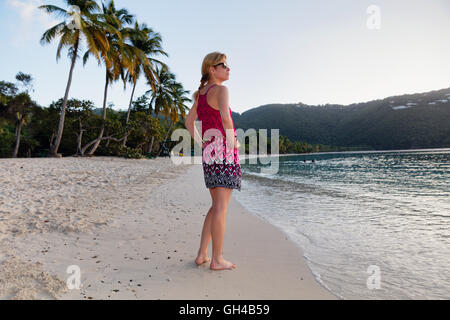 Niedrigen Winkel Blick auf eine Frau stehen am Karibik-Strand barfuß in einem Sommerkleid bei Sonnenuntergang Stunde, Magens Bay, St. Thomas, amerikanische Vir Stockfoto