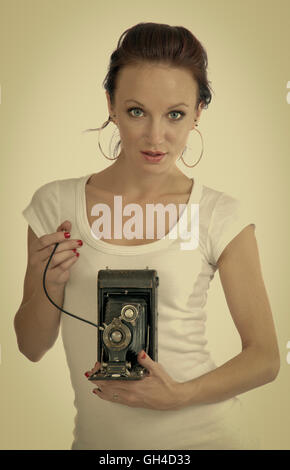 Hübsche junge Frau in ihrem 20 ist ein antikes Faltung Kamera halten. Instagram Retro-look Stockfoto