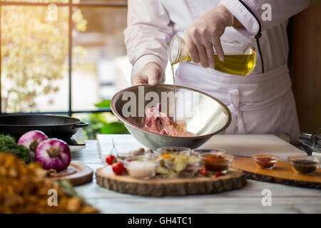 Flüssigkeit gießt auf rohes Fleisch. Stockfoto