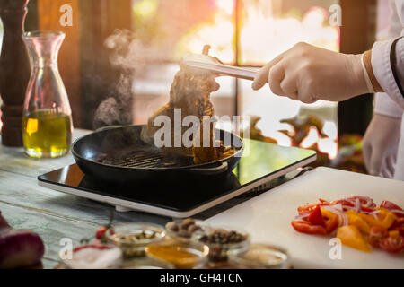 Zange halten gebratenes Fleisch. Stockfoto