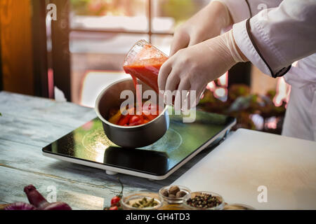 Roter Flüssigkeit gießt in Topf geben. Stockfoto