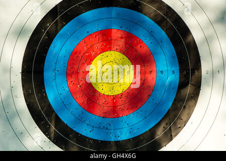 Zielscheibe mit Pfeil Löcher. Gold, rot, blau und schwarz Wettbewerb Ziel markiert wo Pfeile eingedrungen sind Stockfoto