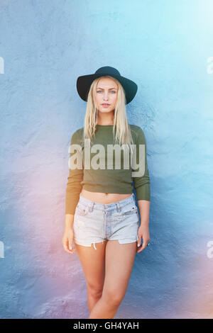 Porträt von hübschen jungen weiblichen Model posiert gegen blaue Wand. Attraktive junge Frau in Casuals. Stockfoto