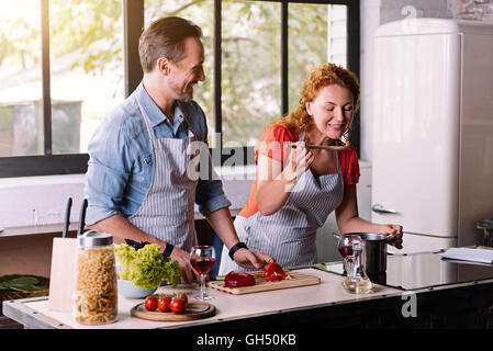 Frau, die versucht einer Gericht gekocht mit Ehemann Stockfoto