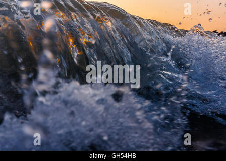 Nahaufnahme einer brechenden Welle bei Sonnenuntergang Stockfoto