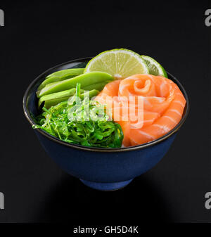 Seetang Salat mit Lachs, Avocado und Kalk im japanischen Stil auf schwarzem Hintergrund Stockfoto