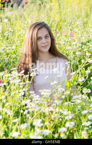 Mädchen sitzt auf Wiese mit Wildblumen Stockfoto